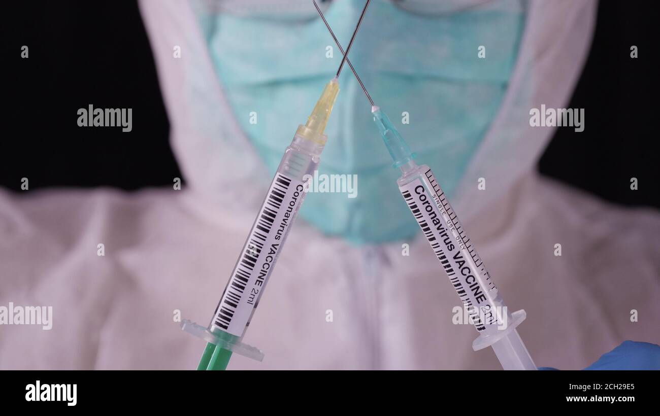 Coronavirus-Impfstoff. Mann in weißer Sicherheitsuniform, Maske und Brille mit Coronavirus-Impfstoffampulle und Spritze. COVID-19 Pandemieheilungskonzept Stockfoto