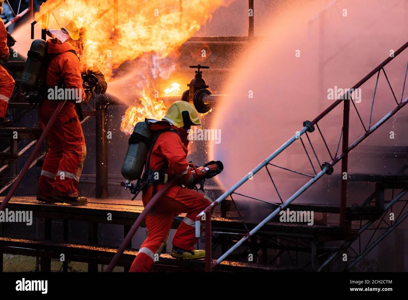 Feuerwehrteam mit Wasser Nebel Art Feuerlöscher zu kämpfen Mit der Flamme aus der Ölleitung Leck und Explosion auf Öl-Bohrinsel und Erdgas-Sta Stockfoto