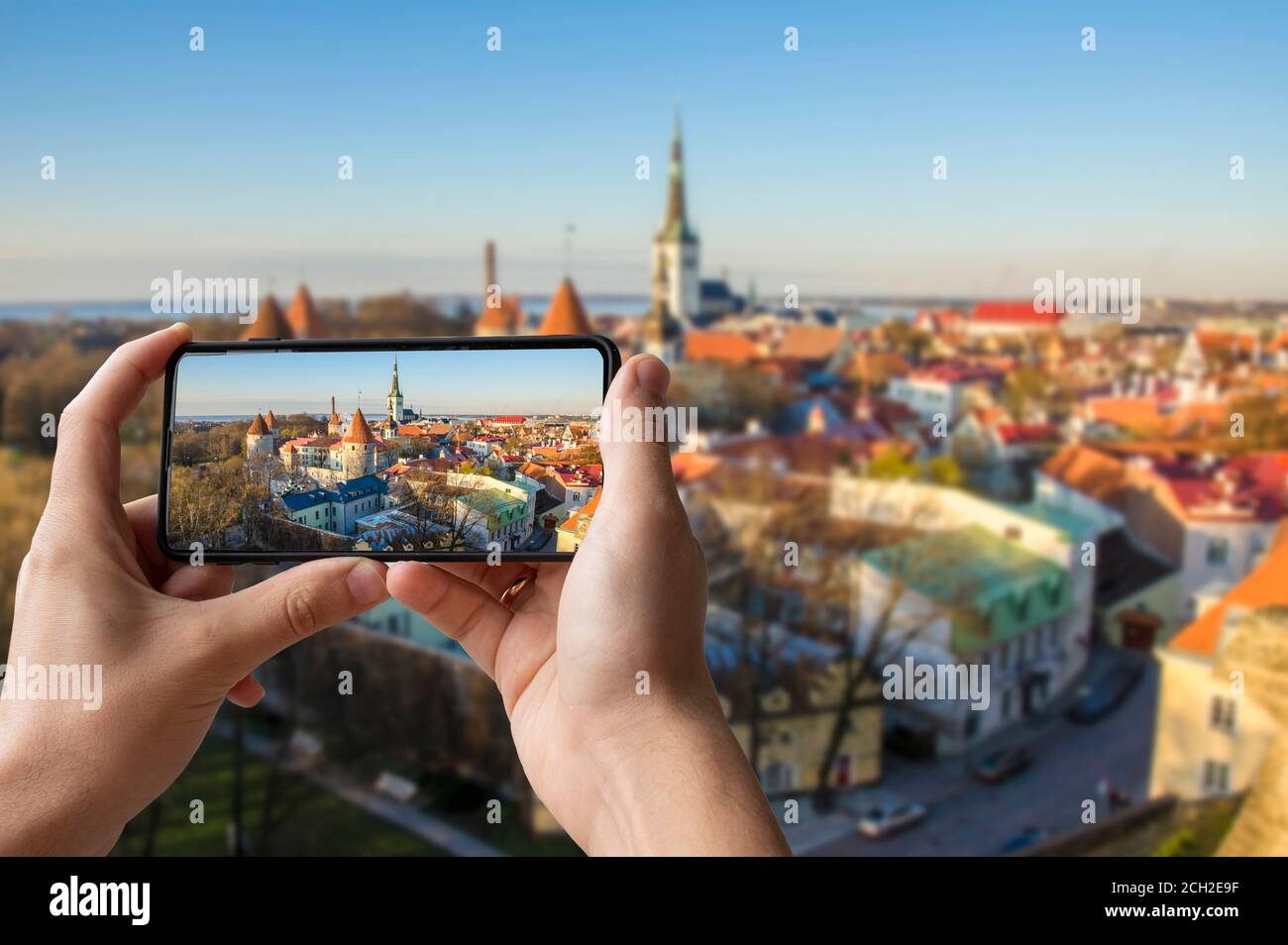 Touristen fotografieren das Stadtzentrum von Tallinn. Mann, der Telefon hält und Fotos von den Türmen Tallinns macht. Blick von oben auf Tallinn Stadtzentrum f Stockfoto