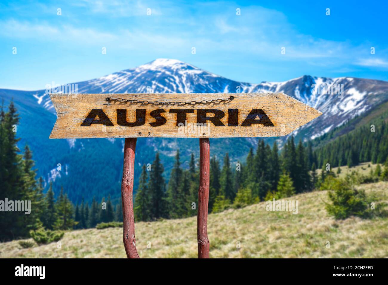 Österreich Holzpfeil Straßenschild gegen Berglandschaft. Reise nach Österreich Konzept. Stockfoto