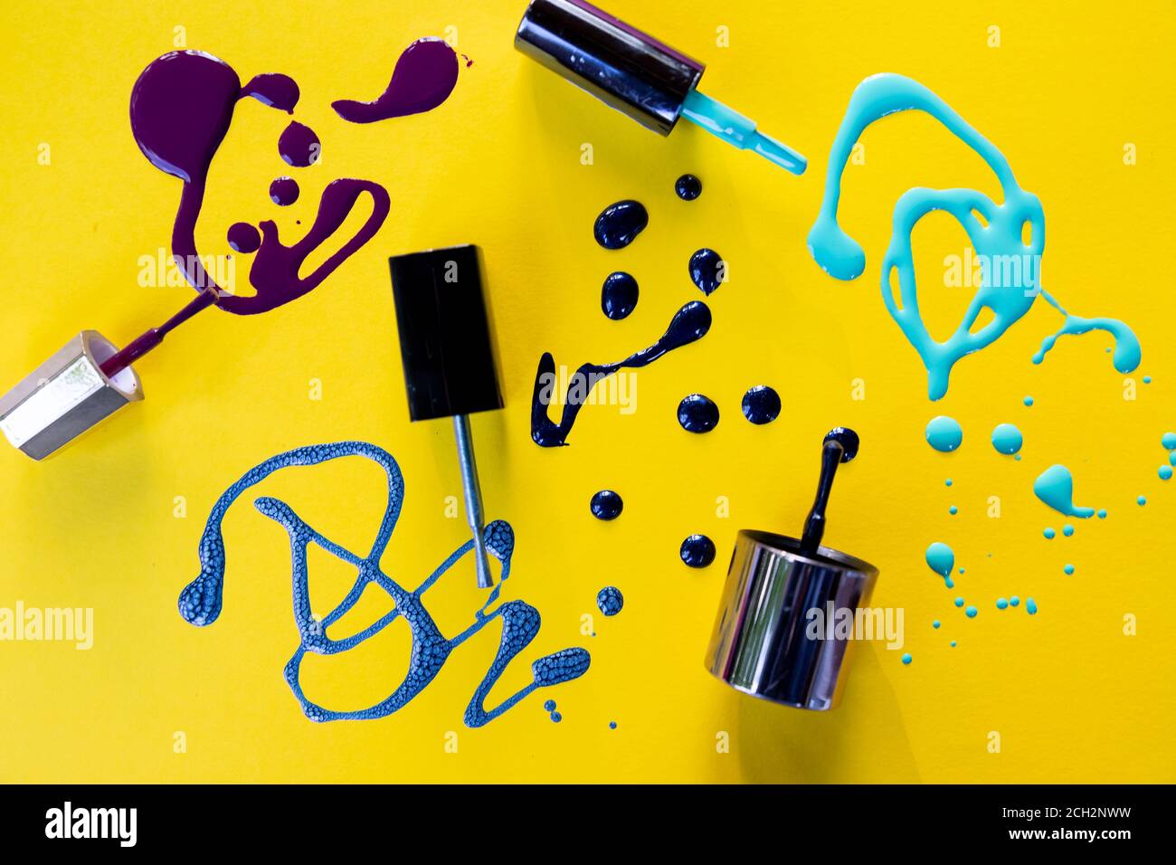 Spritzer von lila Nagellack gefroren in Bewegung auf gelbem Hintergrund.Blau und lila Farbe Splash.Beautiful Nagellack Muster.Nagellack Tropfen. Stockfoto