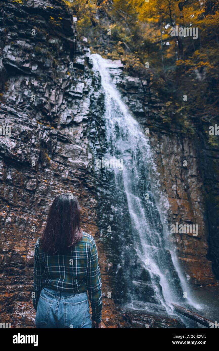 Frau in legerer Kleidung mit Blick auf den Wasserfall Stockfoto