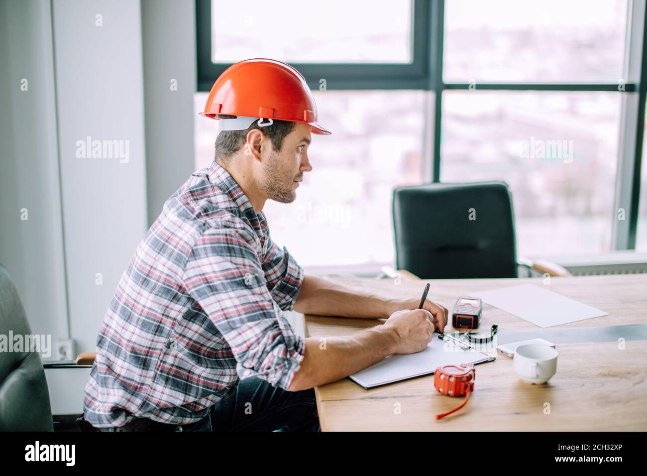 Seriöse selbstmotivierte Baumeister schreibt den Plan der Arbeit in den Notizblock. Seitenansicht close up Portrait Stockfoto