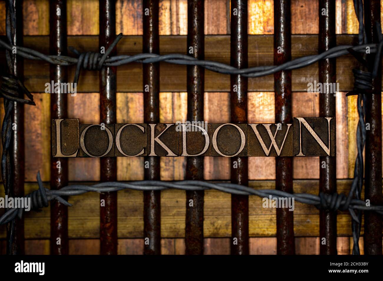 Lockdown Text durch echte authentische Satzbuchstaben auf vintage gebildet Strukturierte rostige Grunge-Nägel mit Stacheldraht auf Bronze-Kupfer Und Gold Hintergrund Stockfoto