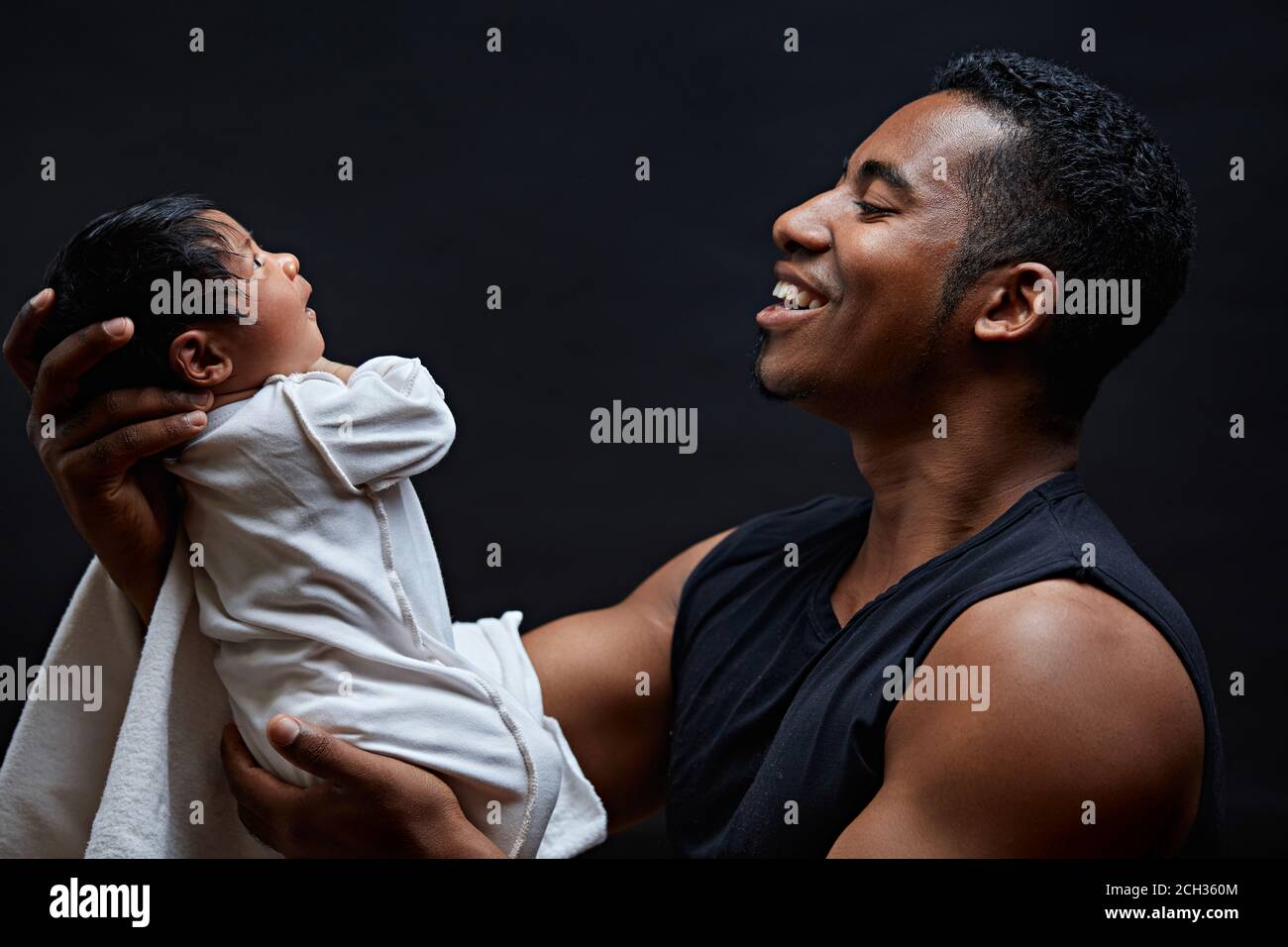 Väterliche Liebe. Nahaufnahme Seitenansicht Porträt eines glücklichen Mannes mit seinem Baby, isoliert schwarzen Hintergrund. Baby sieht aus wie sein Papa Stockfoto