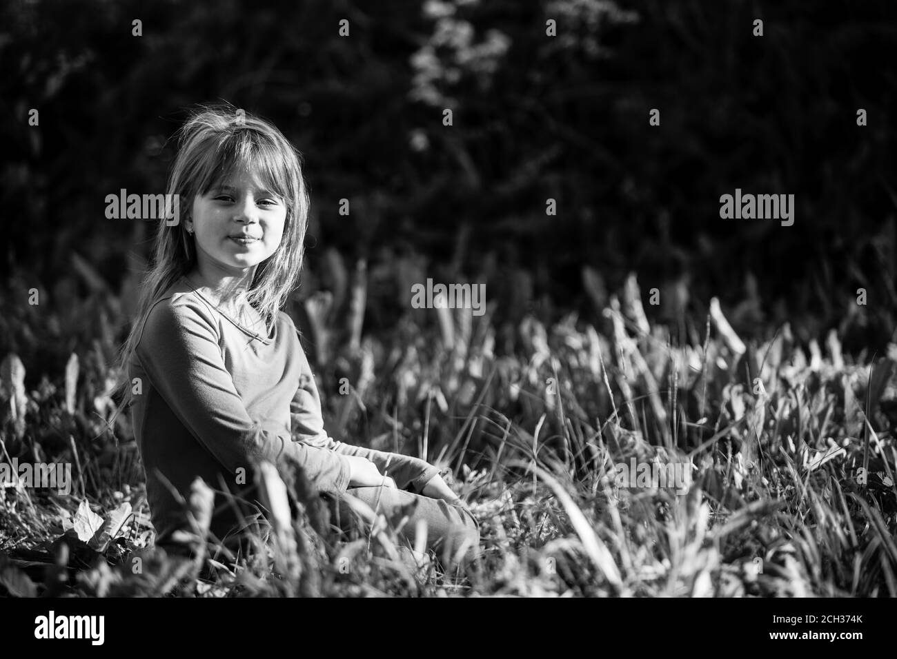 Nettes kleines Mädchen im Gras im Park liegen. Schwarzweiß-Fotografie. Stockfoto