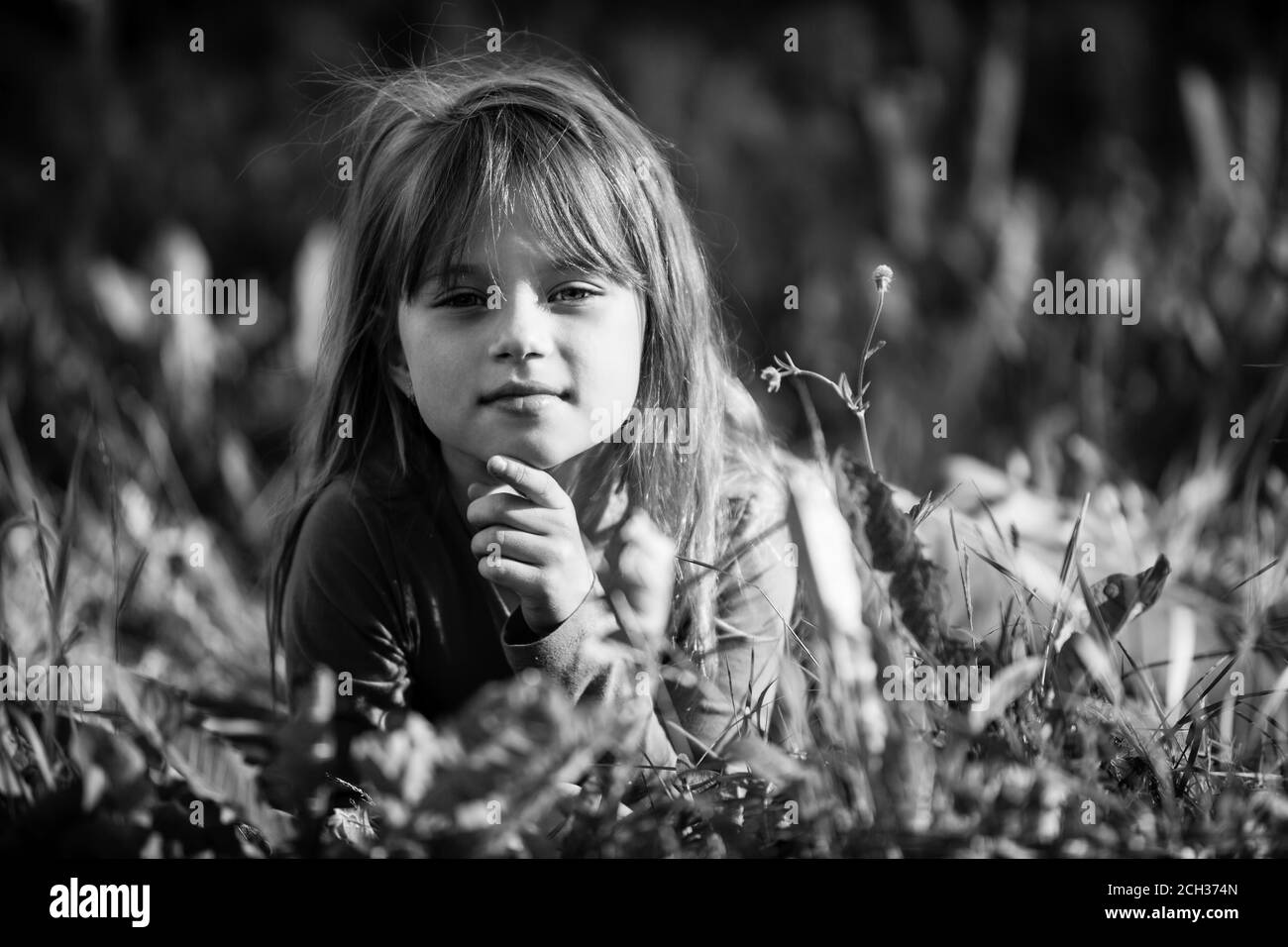Nettes kleines Mädchen liegt im Gras. Schwarzweiß-Foto. Stockfoto
