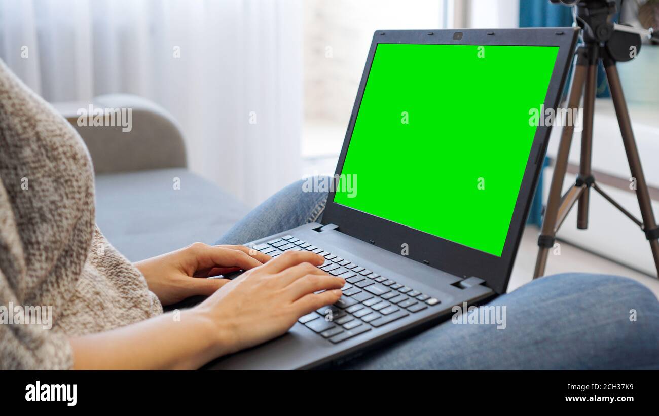 Bloggerin, die am Laptop arbeitet. Ansicht der Kamera auf Stativ und Laptop mit grünem Bildschirm Chromakey - Nahaufnahme Stockfoto