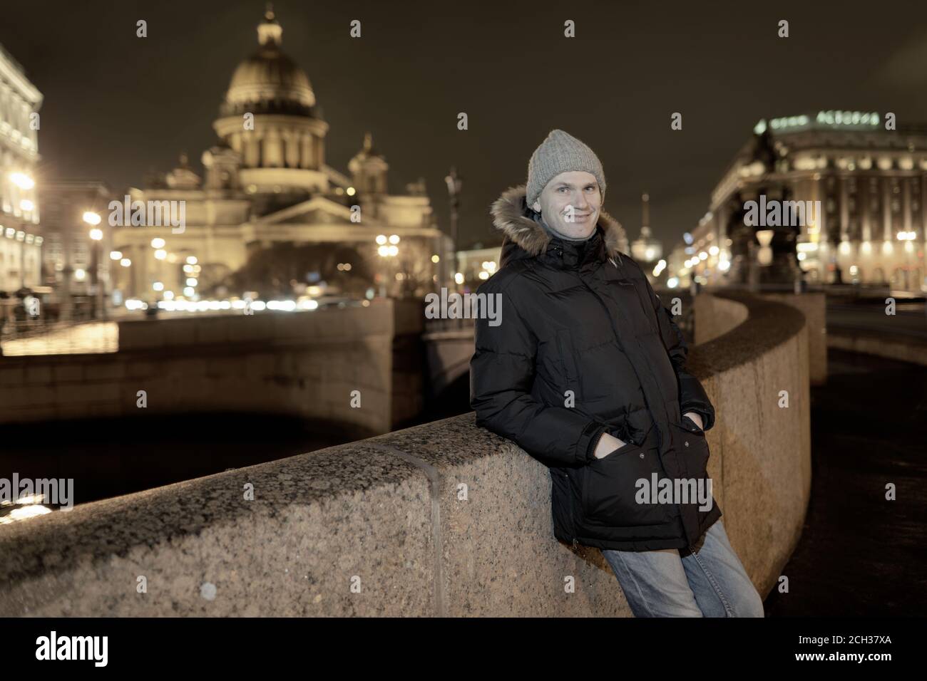 Kaukasischen Mann in Winterjacke lehnt sich an den Zaun der Böschung des Flusses Moika gegen St. Isaac Kathedrale in Sankt-Petersburg, Russland, und suchen Stockfoto