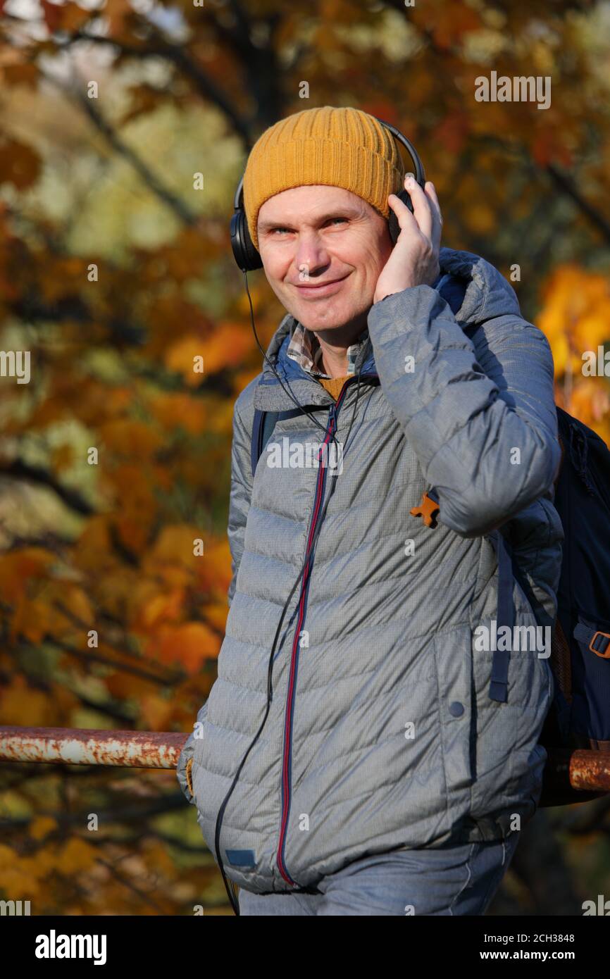 Mann mit Kopfhörern, der Musik von seinem Smartphone im Freien hört An einem sonnigen Herbsttag Stockfoto
