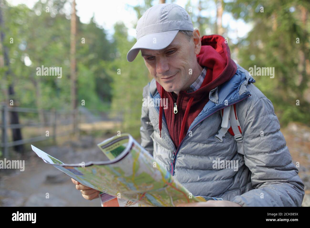 Reifer Kaukasischer Mann mit Rucksack hält eine touristische Karte in Ein Wald Stockfoto