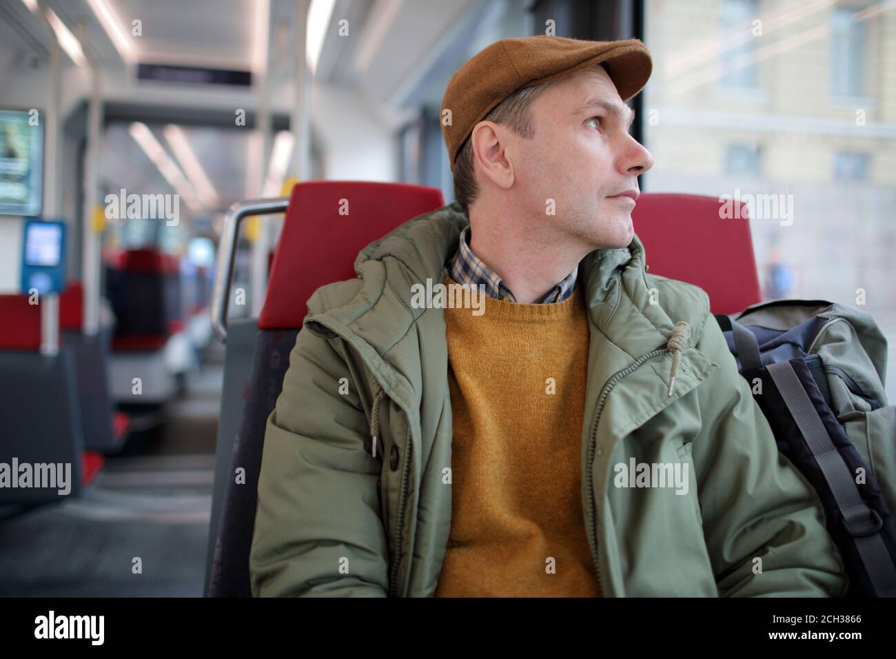 Reifer kaukasischer Mann mit Rucksack Blick durch das Fenster in Eine Straßenbahn Stockfoto