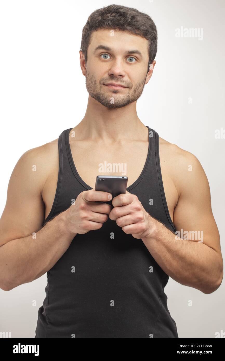 Nahaufnahme Porträt von wunderschönen Mann in Singlet mit Handy. Neue Technologie-Konzept Stockfoto