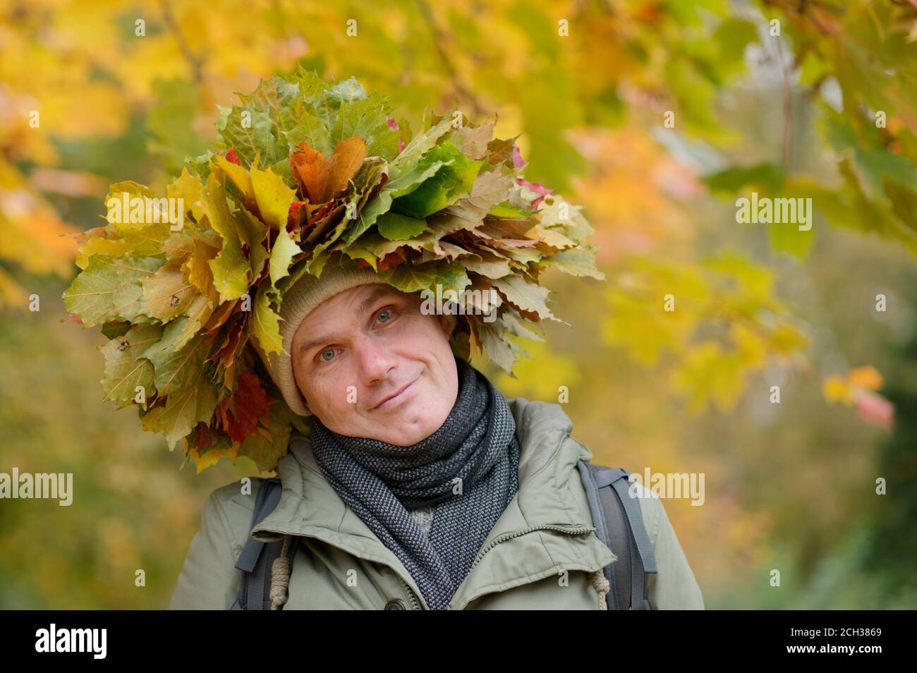 Mann im Herbstkranz mit roten und orangefarbenen Blättern An die Kamera Stockfoto