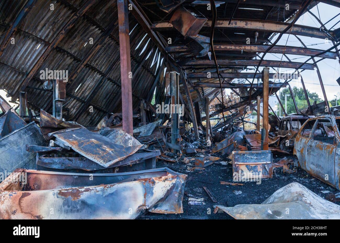 Eingestürztes Dach, verworrter Schrott und freiliegender Stahl in ausgebrannter Autogarage Stockfoto
