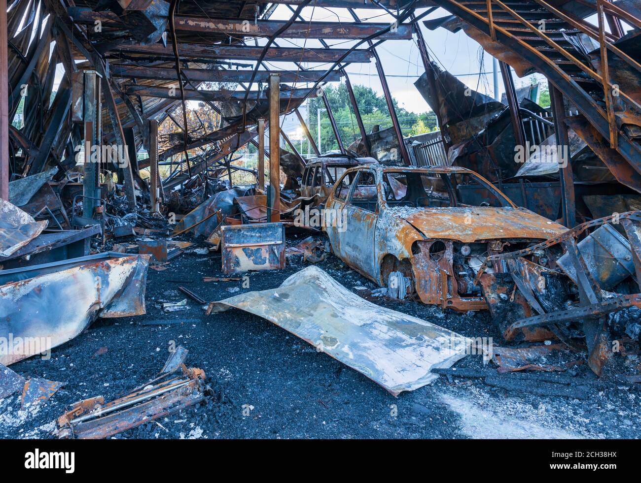 Zerstörte Autos inmitten der Masse des ausgebrannten Metalls nach dem Brand In der Garage Stockfoto
