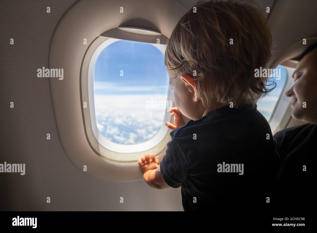 Nettes Kleinkind zeigt seinen Finger auf den Himmel durch das Fenster. First Flight Konzept, Reisen mit Kindern. Stockfoto