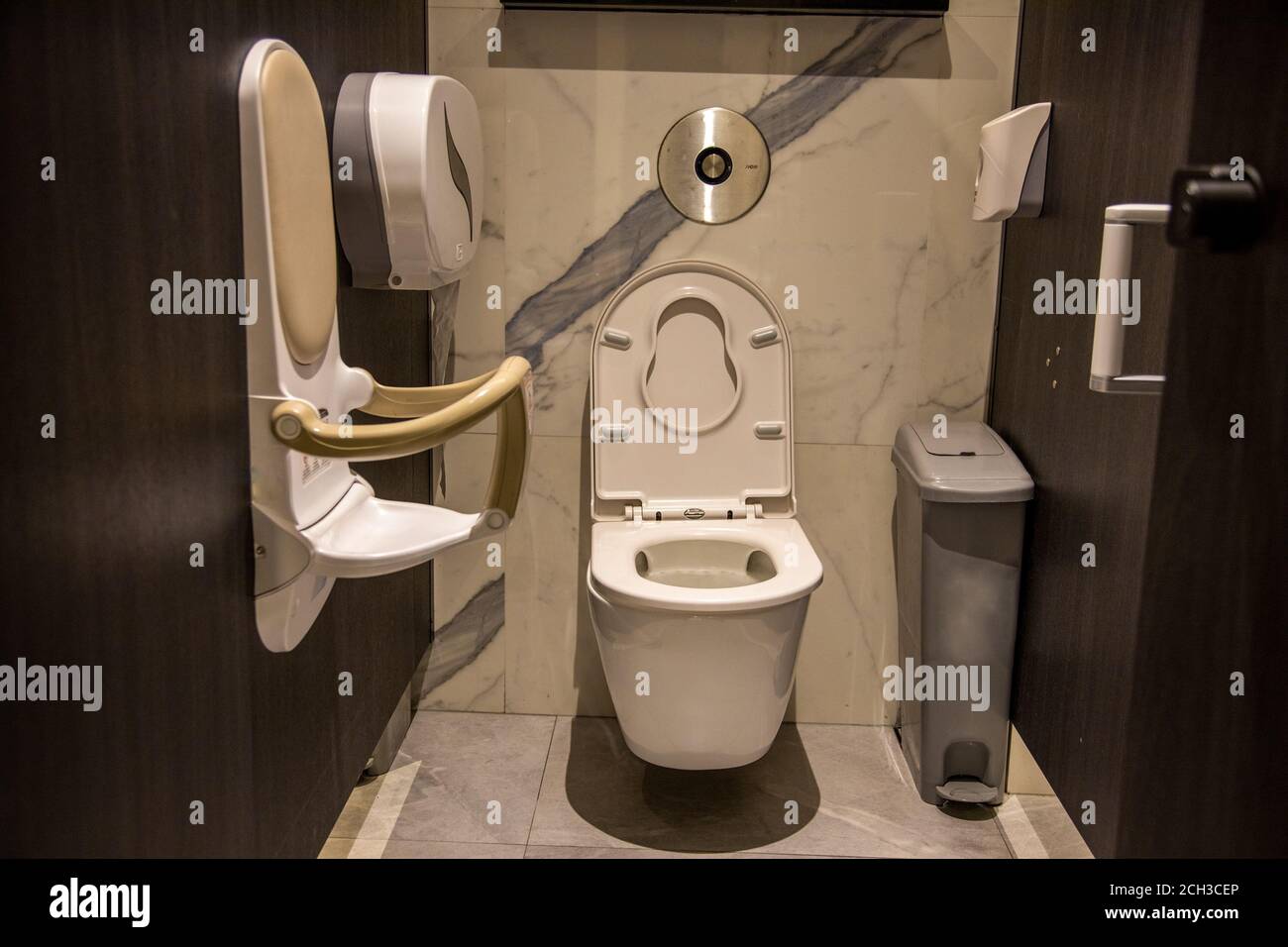 Mutter Pflege öffentlich WC-Ausrüstung. Kabine einer öffentlichen Toilette ausgestattet Klappbare Kleinkind Sicherheitsstuhl an der Wand in der öffentlichen Toilette montiert. Freundlich zu Stockfoto