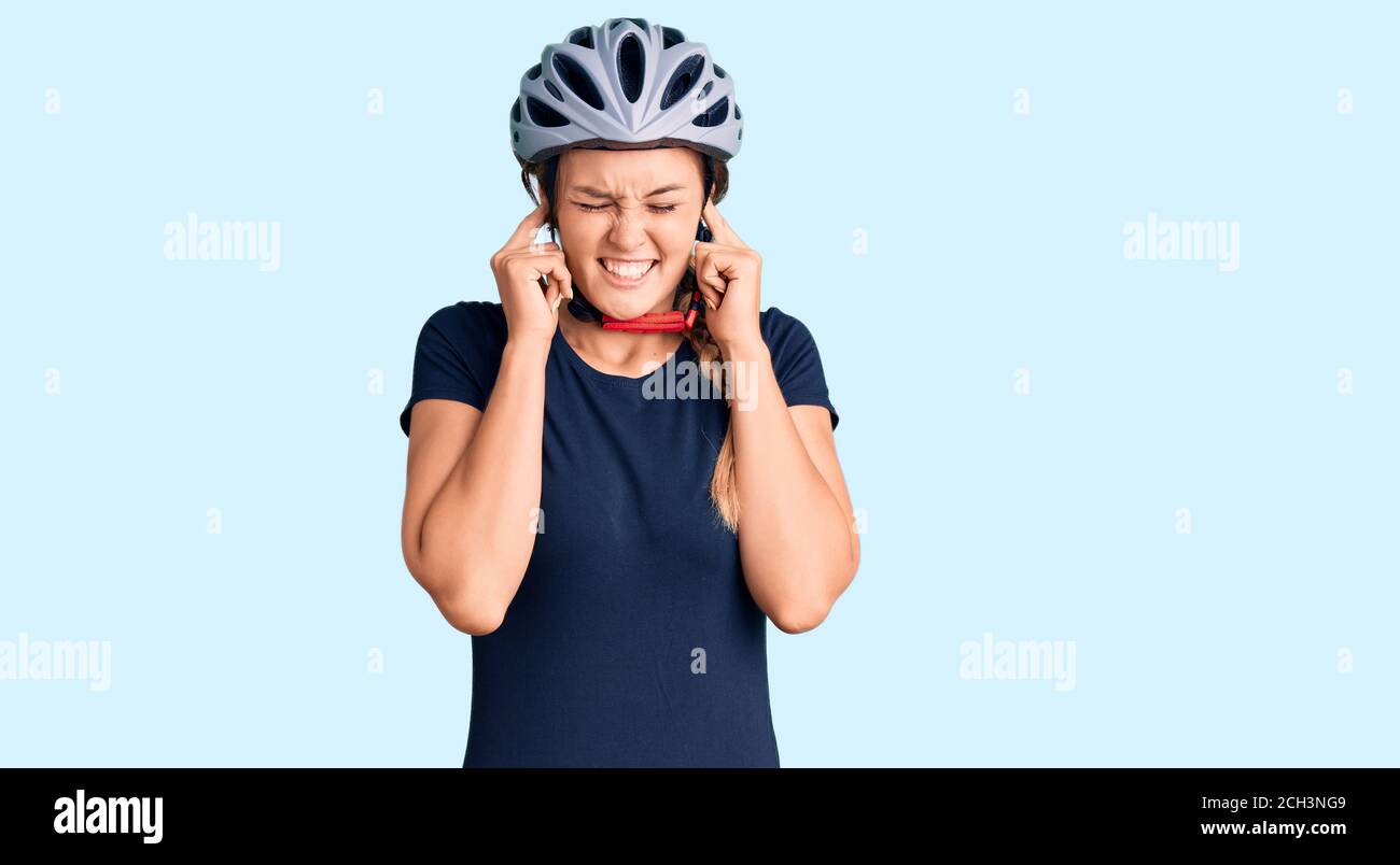 Schöne kaukasische Frau trägt Fahrradhelm über Ohren mit Fingern mit  verärgerten Ausdruck für den Lärm der lauten Musik. Taub Konzept  Stockfotografie - Alamy