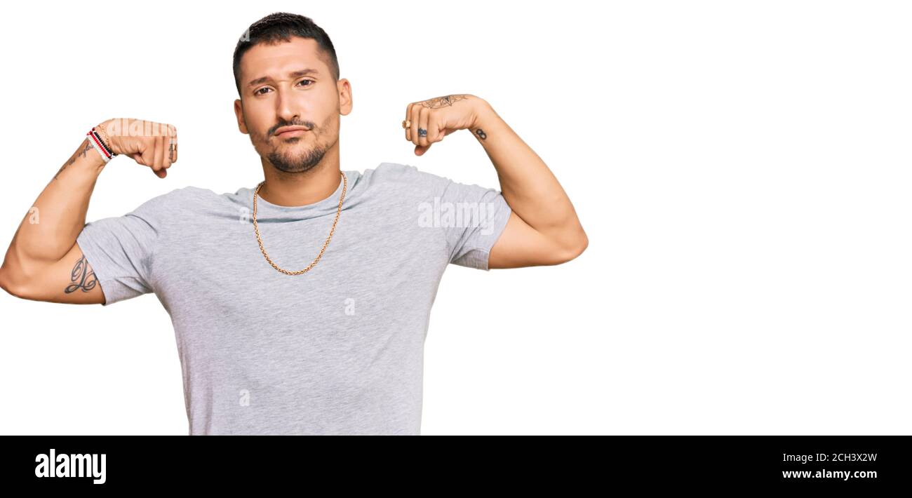 Schöner Mann mit Tattoos tragen 90s Stil zeigt Arme Muskeln lächelnd stolz. Fitness-Konzept. Stockfoto
