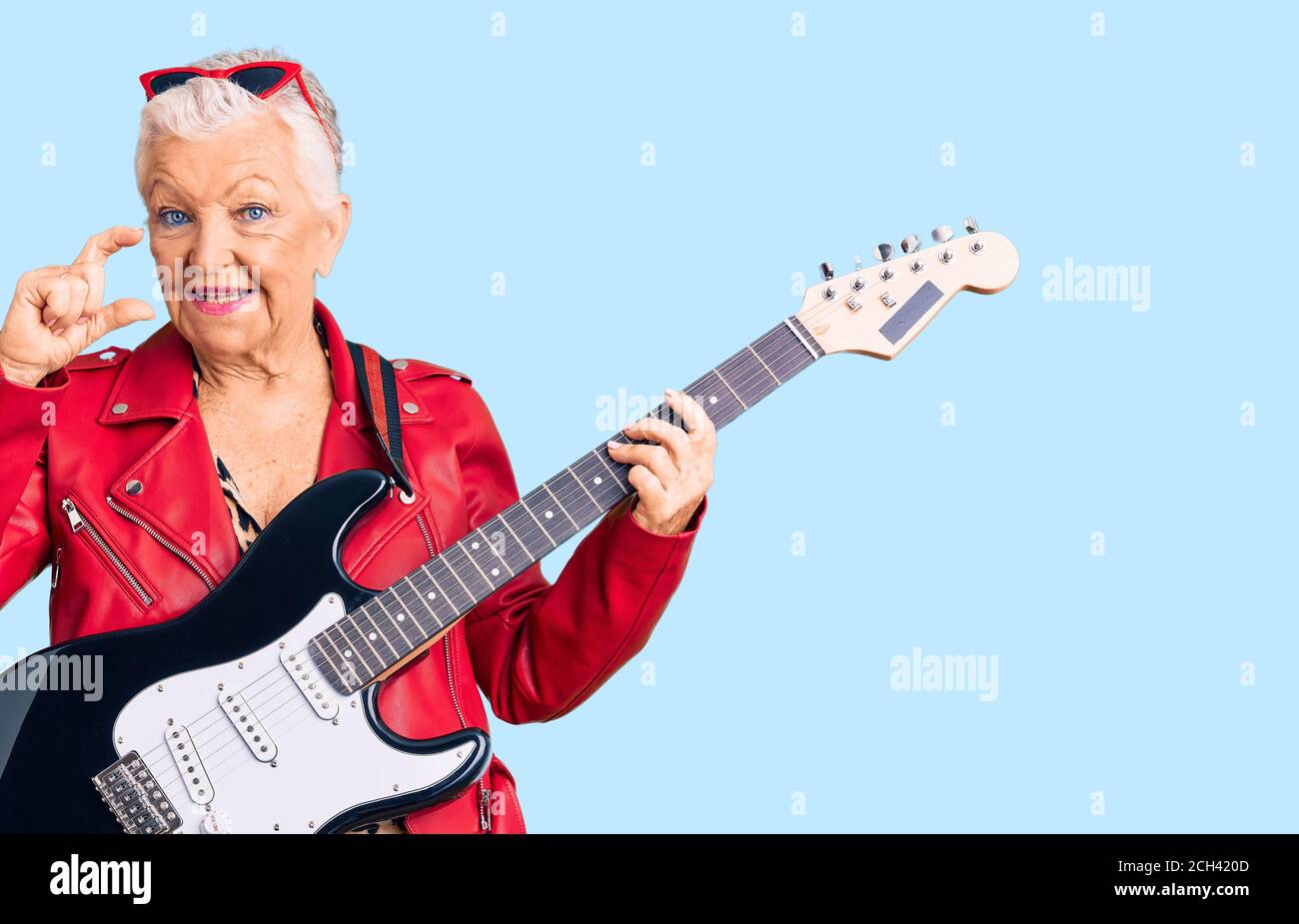 Ältere schöne Frau mit blauen Augen und grauen Haaren tragen Ein moderner Look spielen E-Gitarre lächelnd und zuversichtlich Gestik Mit der Hand tun Smal Stockfoto