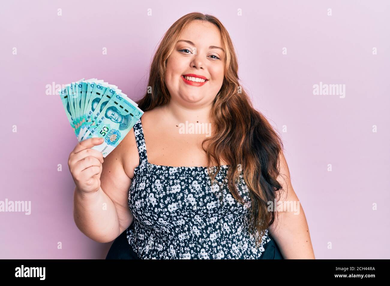 Plus Größe kaukasische junge Frau mit 50 Yuan chinesischen Banknoten Schauen positiv und glücklich stehen und lächeln mit einem selbstbewussten Lächeln zeigt Zähne Stockfoto