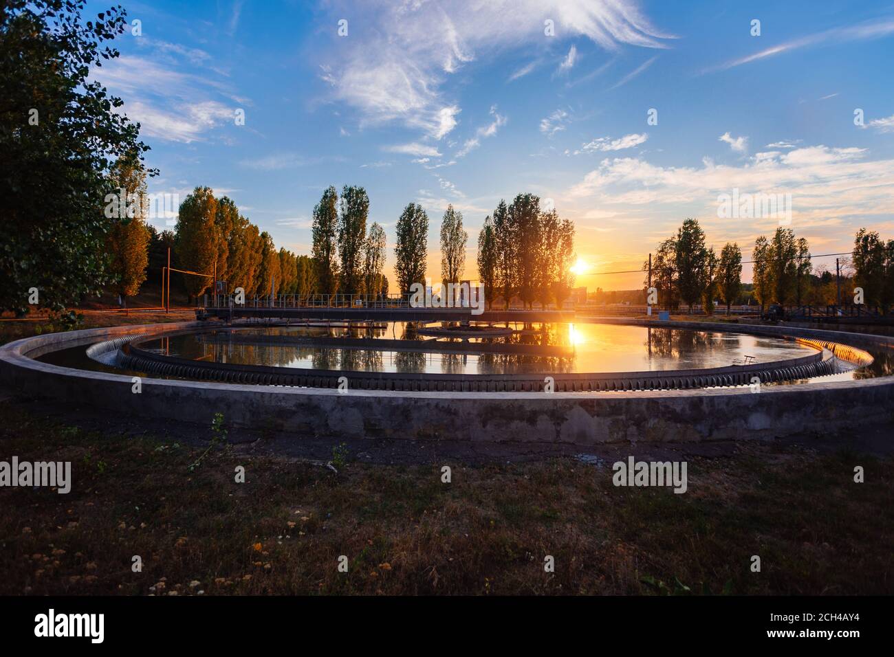 Moderne Kläranlage. Runder Abwasserreinigungsbehälter bei Sonnenuntergang Stockfoto