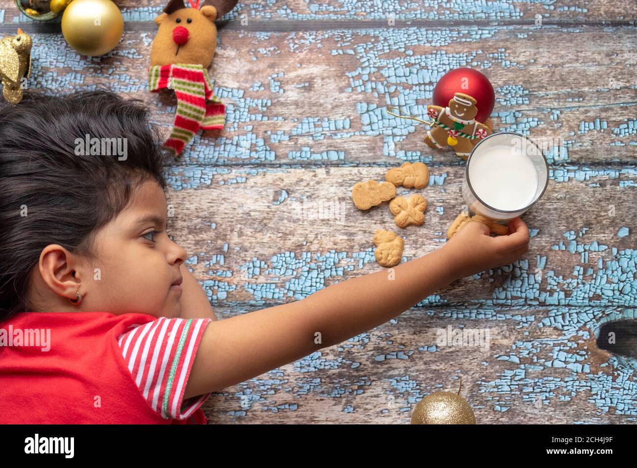 Süße kleine Mädchen spielt mit Santa's Kekse und Milch um Weihnachten Stockfoto