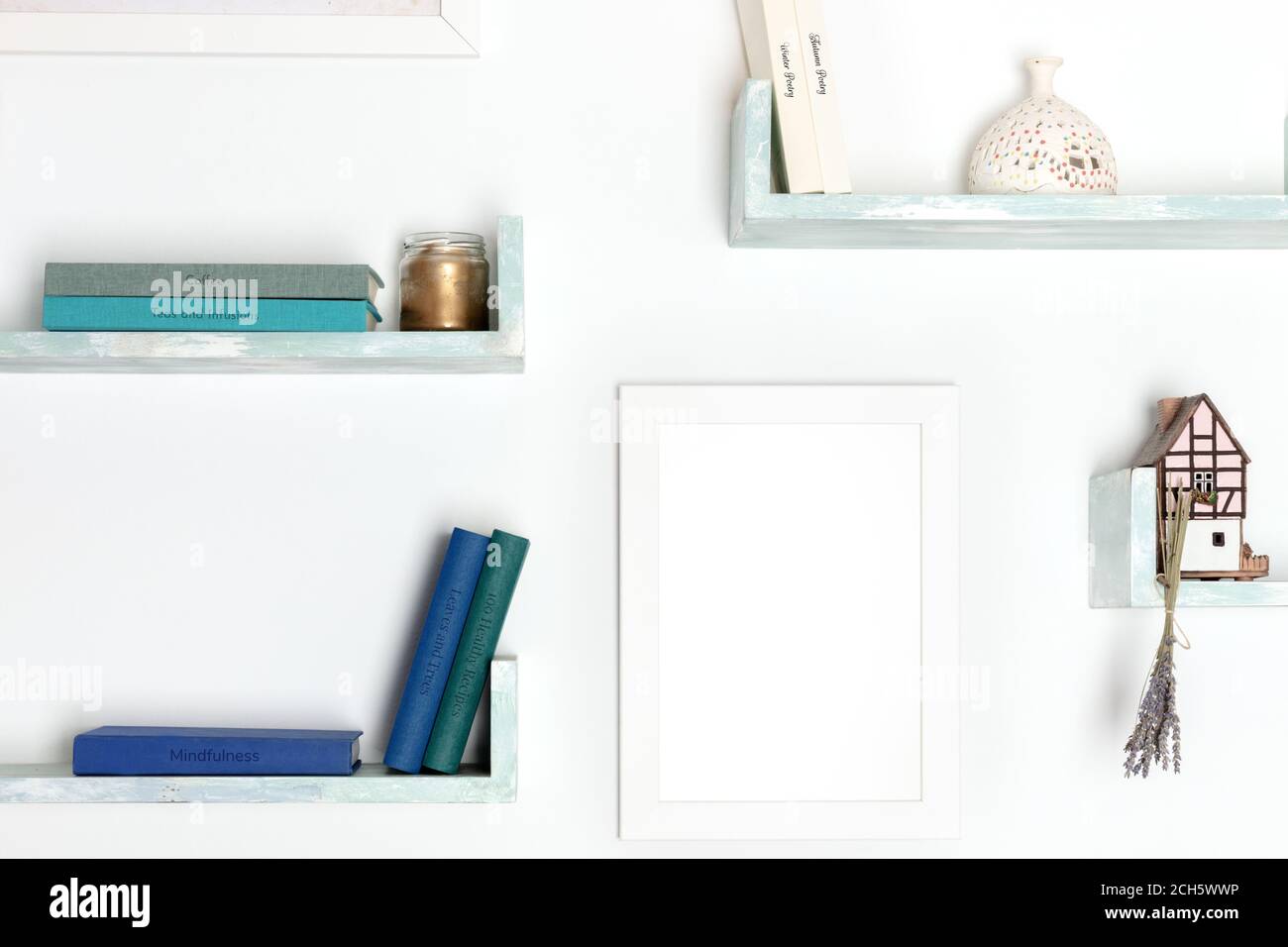 Postermockup. Ein leerer Rahmen für eine Zeichnung an einer Wand mit Büchern und Gegenständen, an einer weißen Wand Stockfoto