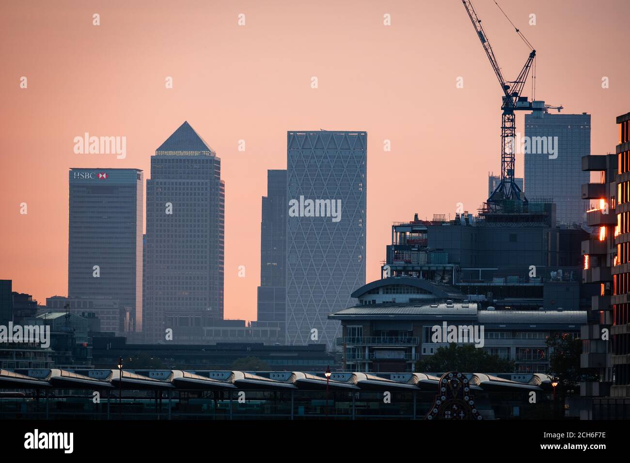 Am frühen Morgen leuchtet das Licht in den Wolkenkratzern von Canary Wharf im Osten Londons, zu Beginn einer Woche, in der Großbritannien voraussichtlich bei Temperaturen von mehr als 30 Grad Celsius fabbern wird. Stockfoto