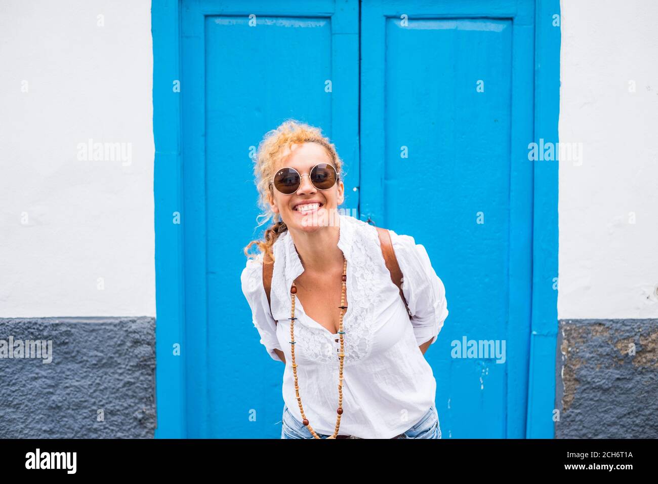 Fröhliche Menschen Porträt mit lächelnden Erwachsenen schöne Frau haben Spaß Draußen mit blau-weißen Tür und Wand Zuhause in Hintergrund - Konzept der Outdoor Stockfoto
