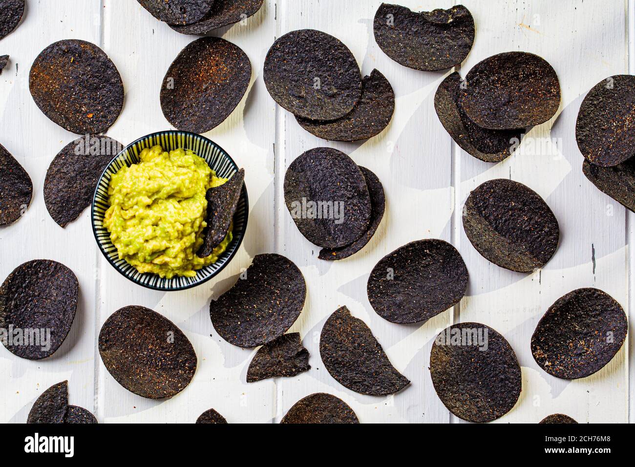 Schwarze Kartoffelchips mit Avocado Dip - Guacamole, weißer Hintergrund. Stockfoto