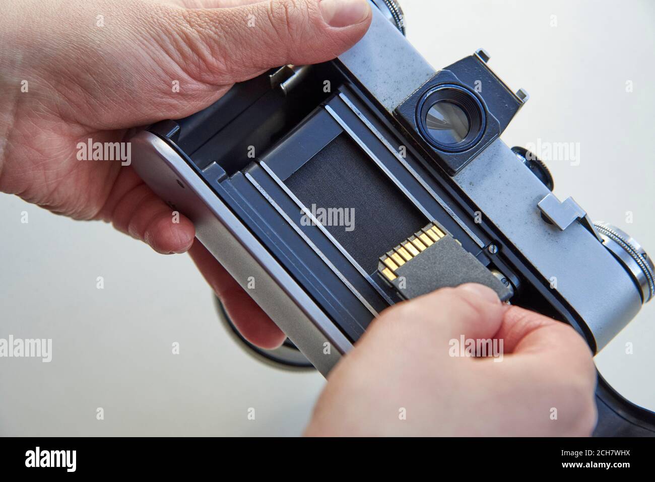 Die Hand, die das USB-Flash-Laufwerk in die Filmkamera einsteckt, das Konzept der Medienwechsel im Laufe der Zeit. Stockfoto