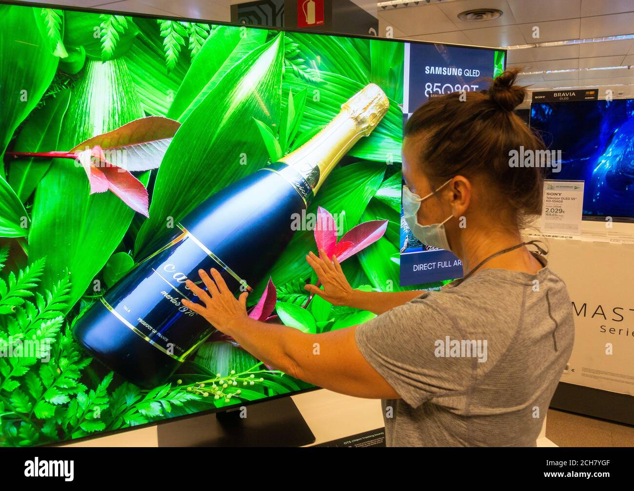 Frau trägt Gesichtsmaske Blick auf Samsung High Definition QLED 8K Q850T Fernseher, TV-Bildschirm im Geschäft. Stockfoto