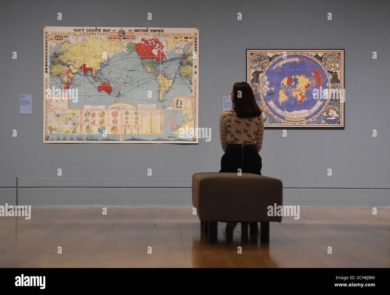Ein Mitarbeiter beobachtet George Philip und Son Ltd's 'Navy League Map of the British Empire (links) und Leslie MacDonald Gills 'Cable & Wireless Great Circle Map', die Teil der kommenden Artist and Empire-Ausstellung sind, die zwischen dem 25. November und dem 10. April in der Tate Britain in London gezeigt wird. Stockfoto