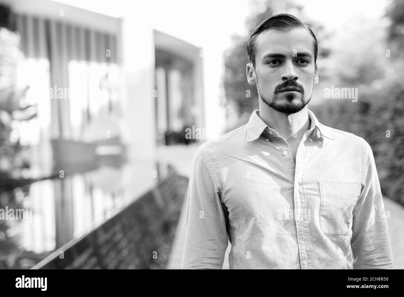 Junger gutaussehender bärtiger Geschäftsmann, der sich in der Stadt entspannt Stockfoto