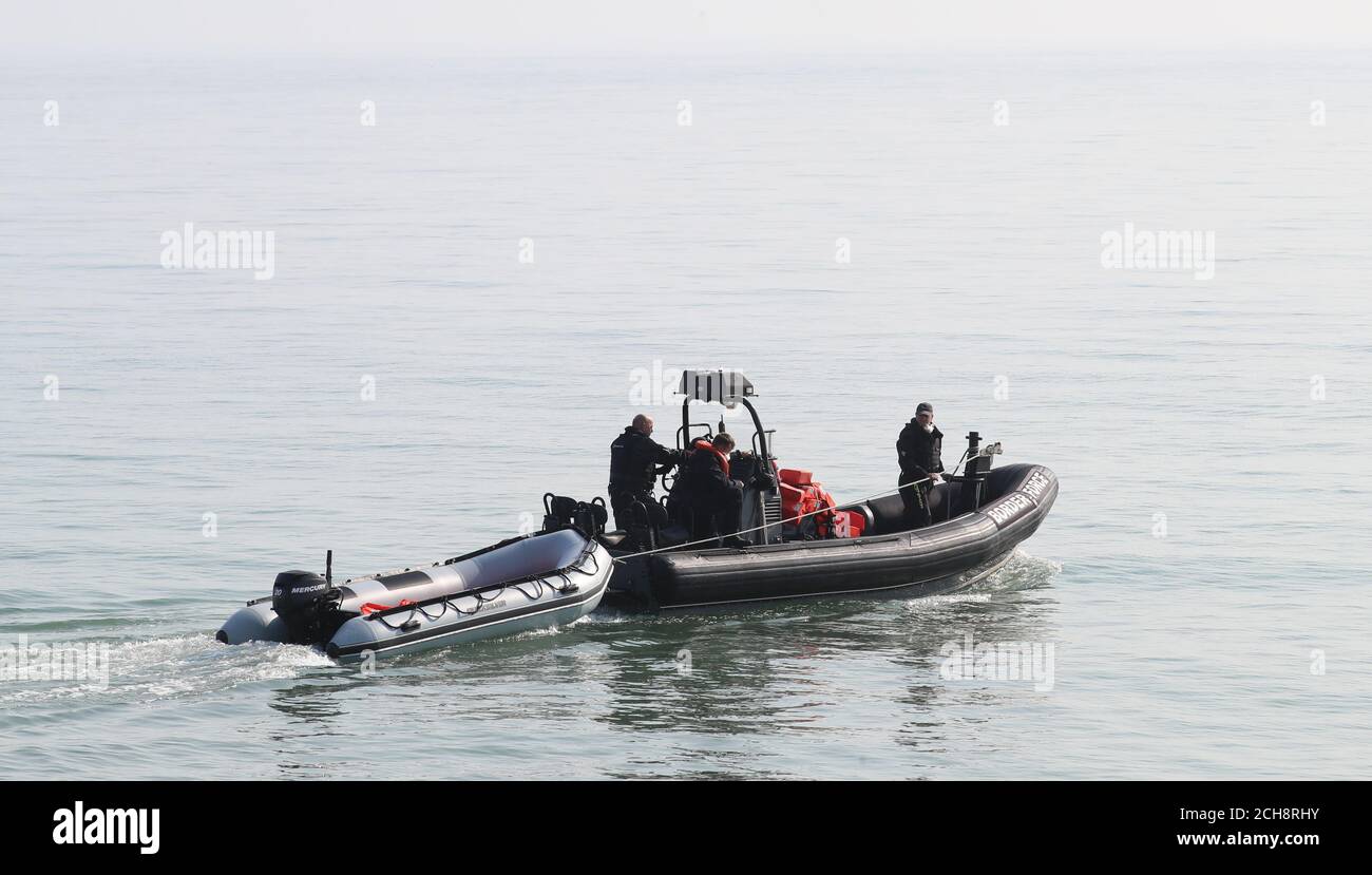 Mitarbeiter der Border Force Bergen ein aufblasbares Boot am Kingsdown Beach in der Nähe von Dover, Kent, wo es von Menschen verlassen wurde, die dachten, es sei Migranten, die es benutzt hatten, um den Ärmelkanal zu überqueren. Stockfoto