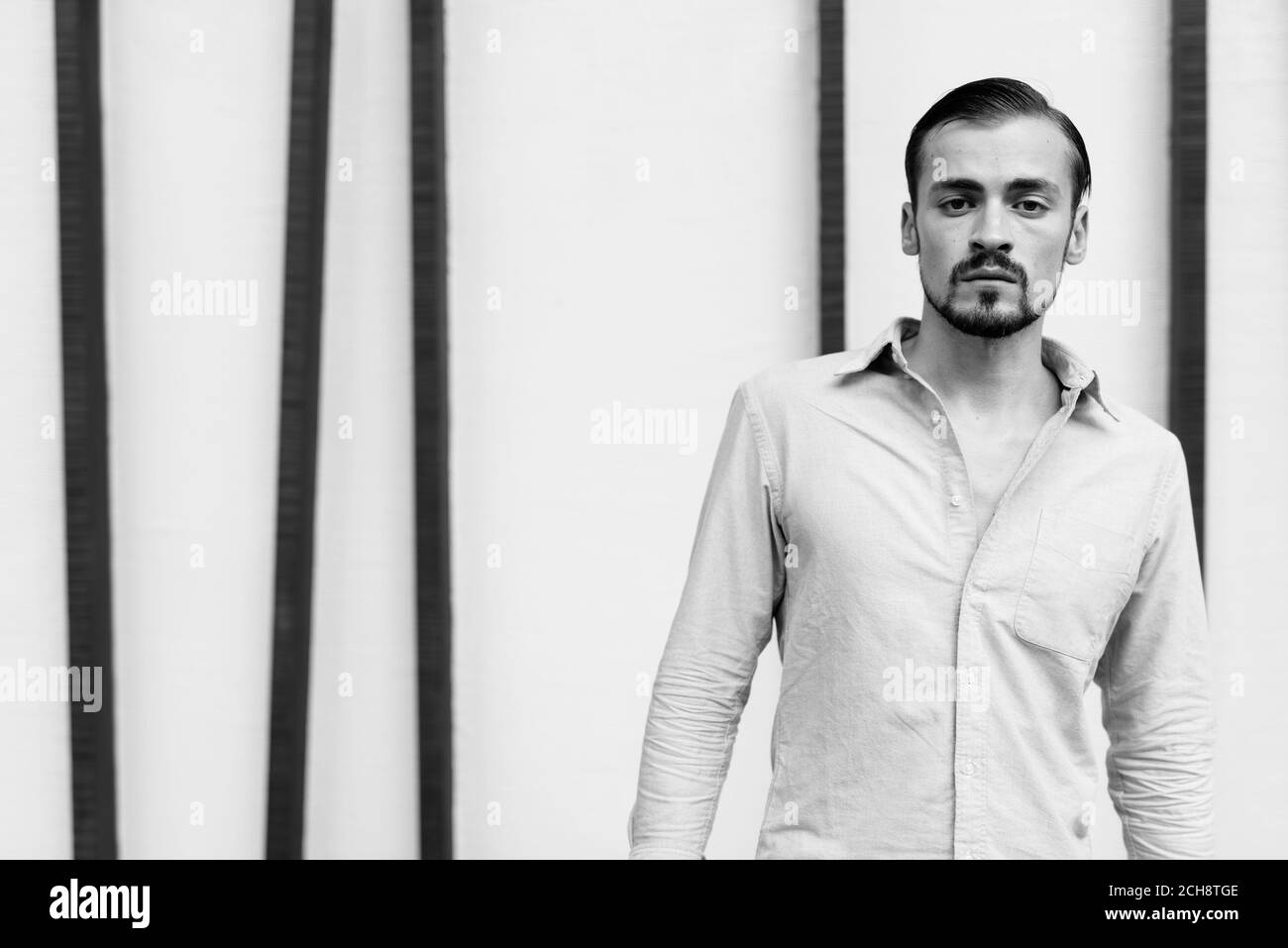 Junger gutaussehender bärtiger Geschäftsmann, der sich in der Stadt entspannt Stockfoto