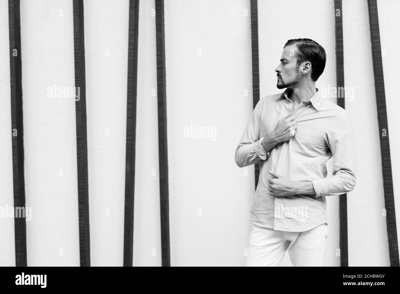 Junger gutaussehender bärtiger Geschäftsmann, der sich in der Stadt entspannt Stockfoto