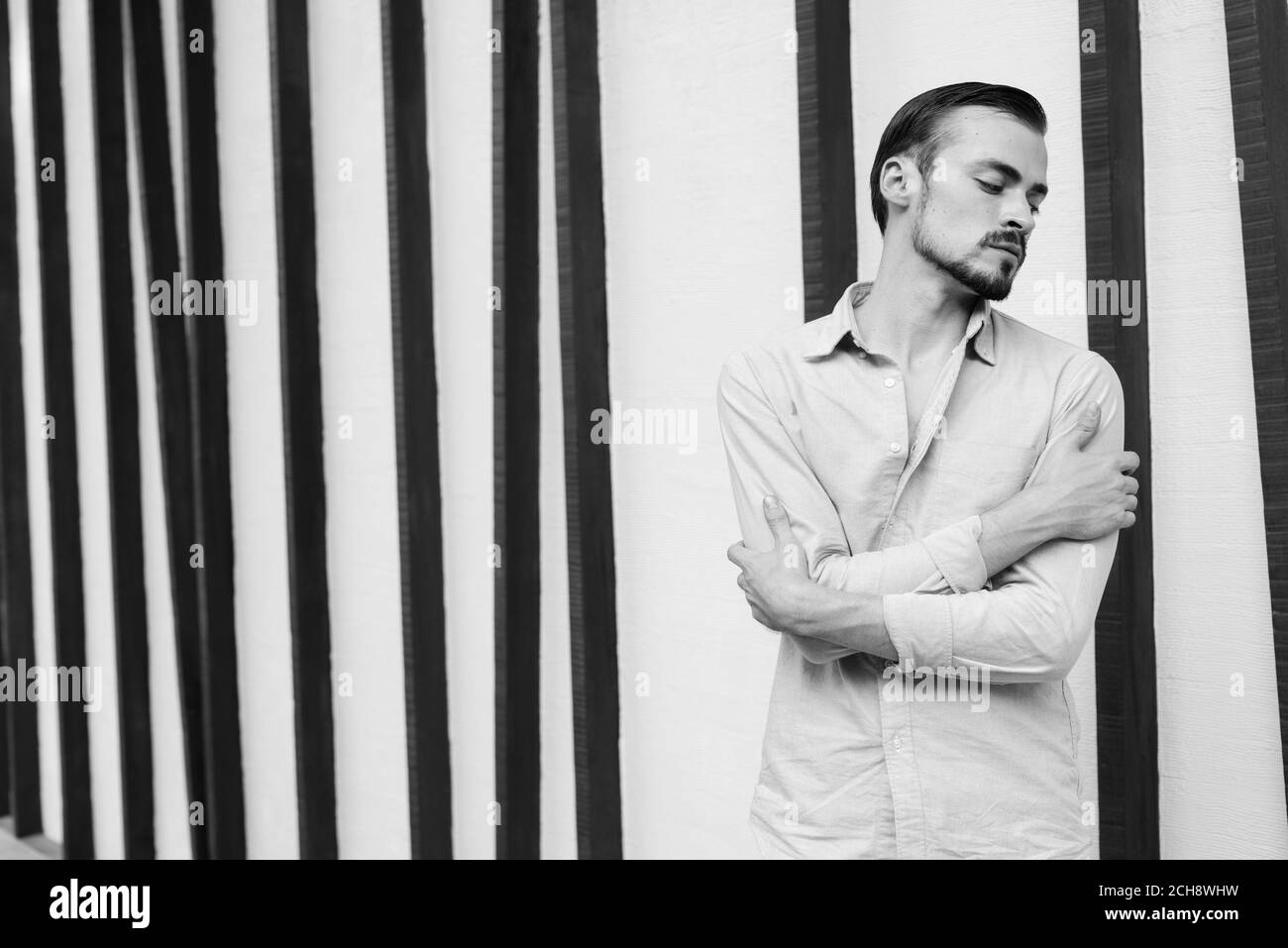 Junger gutaussehender bärtiger Geschäftsmann, der sich in der Stadt entspannt Stockfoto