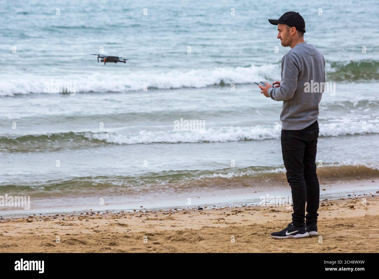 Junger Mann, der eine Drohne bei einer Veranstaltung am Bournemouth Beach, Bournemouth, Dorset UK im September betreibt Stockfoto