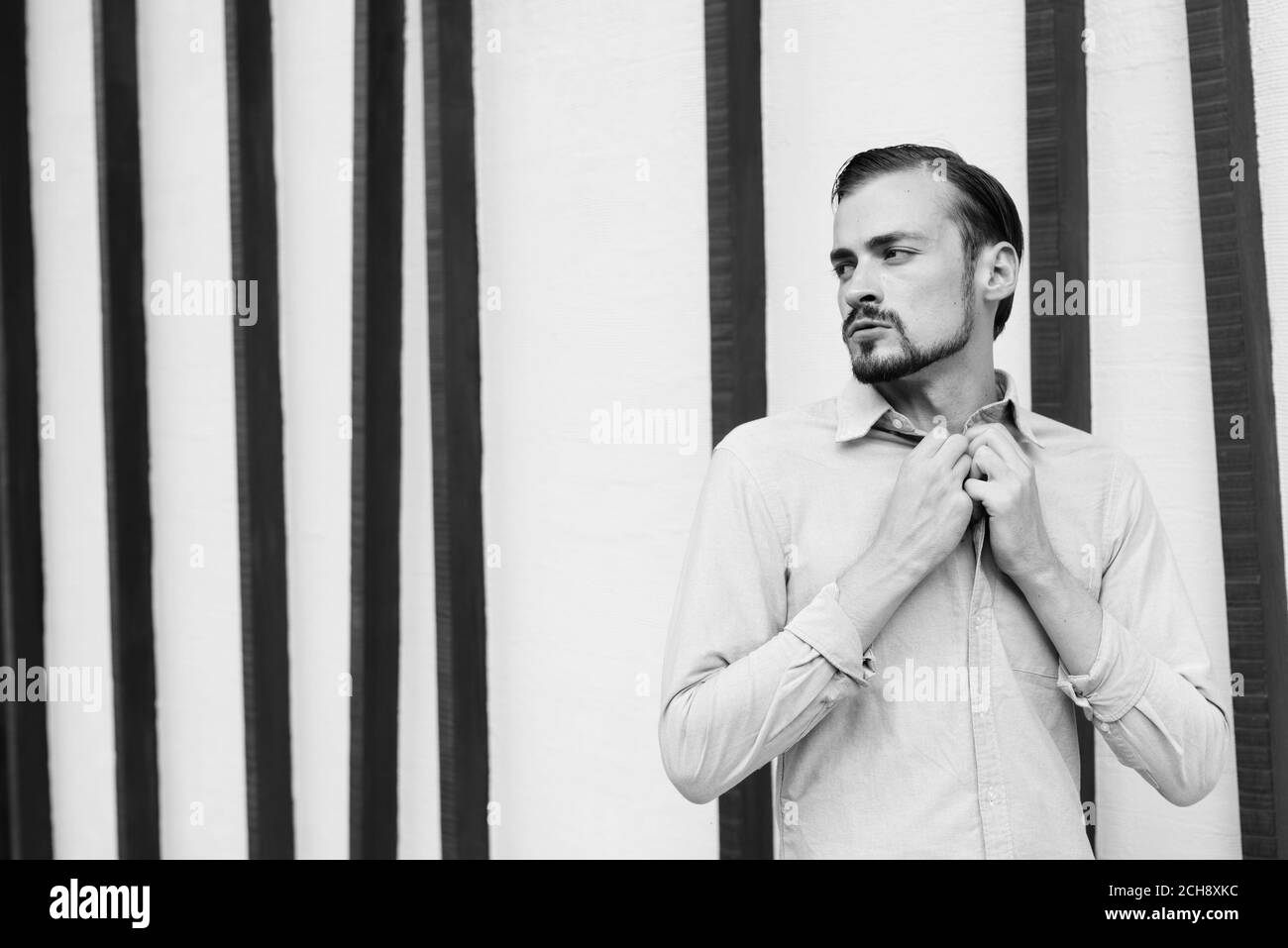 Junger gutaussehender bärtiger Geschäftsmann, der sich in der Stadt entspannt Stockfoto