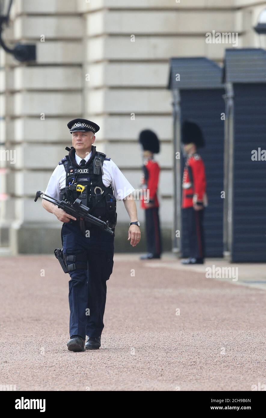 Ein bewaffneter Polizeibeamter und Soldaten der irischen Garde auf dem Vorplatz des Buckingham Palace im Zentrum von London. Scotland Yard hat gesagt, dass ein 41-jähriger Mann festgenommen wurde, nachdem er am Mittwochabend eine Umfassungsmauer am Palast bestochen hatte. Stockfoto