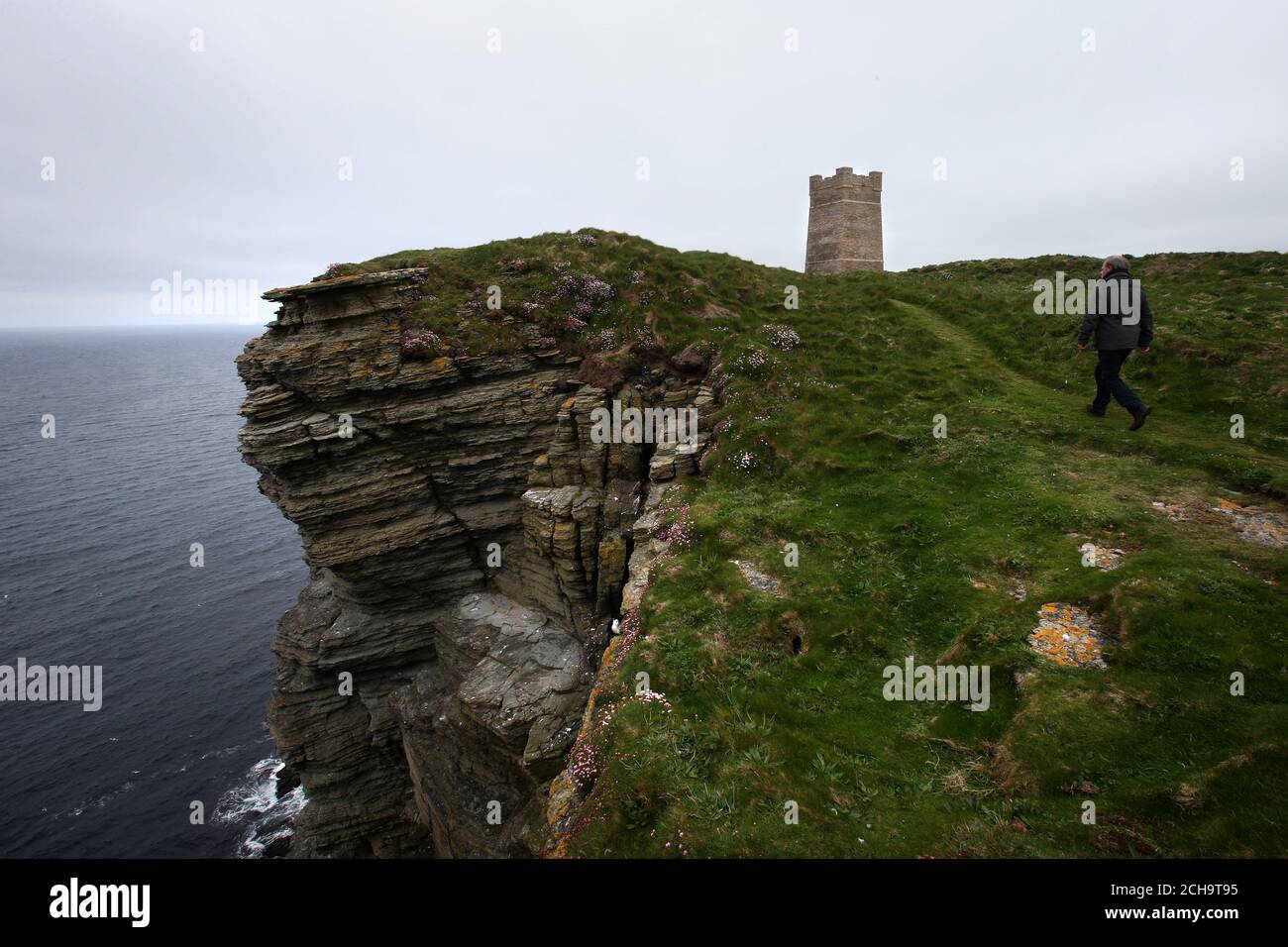 Die Besucher wandern auf den Klippen hoch über dem Meer bei Marwick Head in Orkney entlang, wo der Turm steht, der zur Erinnerung an Lord Kitchener gebaut wurde. Stockfoto