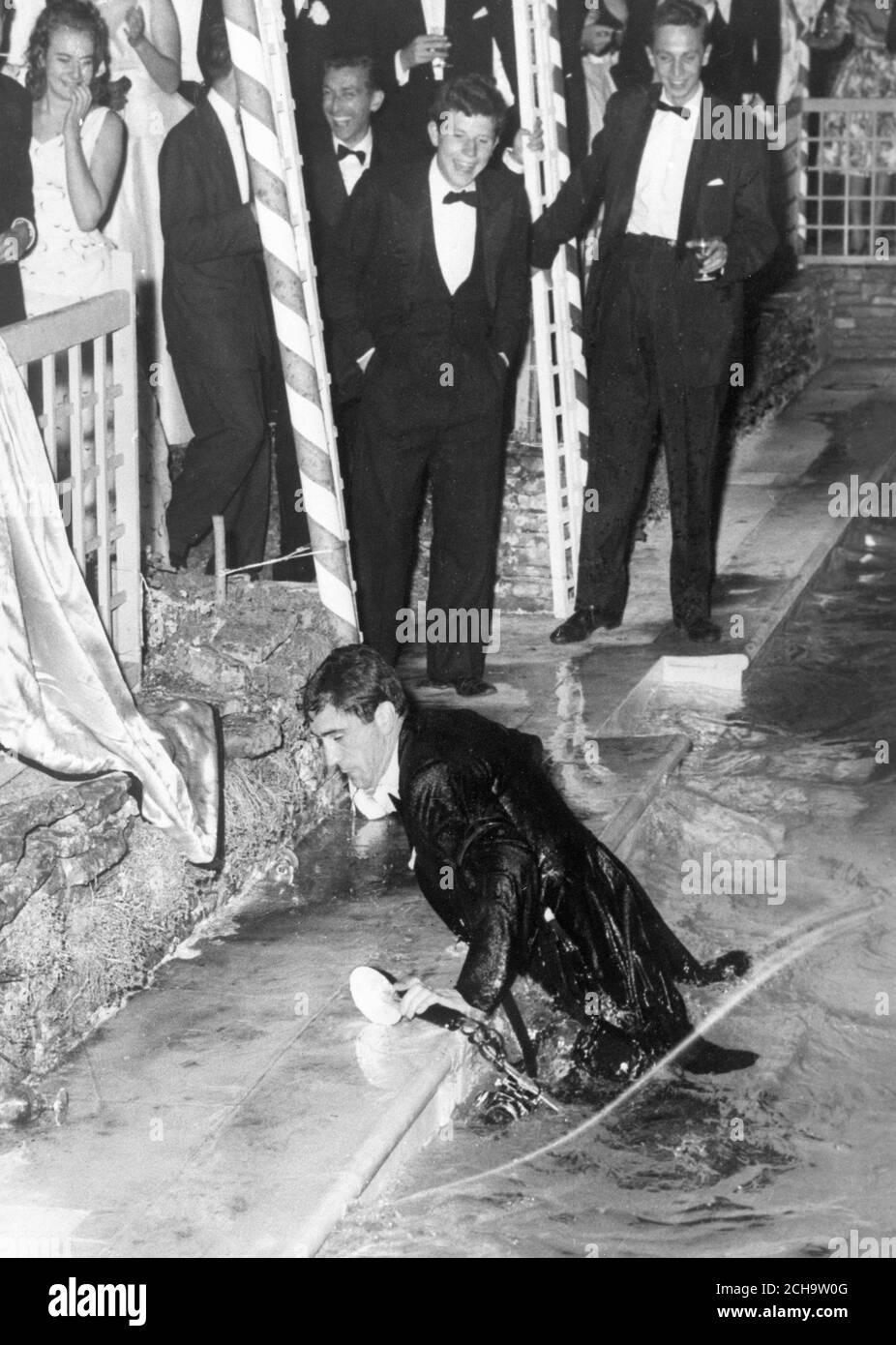 Daily Mail Fotograf David Steen klammert sich an seine Ausrüstung, während er auf der von Paul Getty, dem reichsten Mann der Welt, gegebenen Hauswärmparty aus dem Schwimmbad klettert. Er wurde von Gästen auf der Party in den Pool geworfen, die über seine Lage lachend gesehen werden. Stockfoto