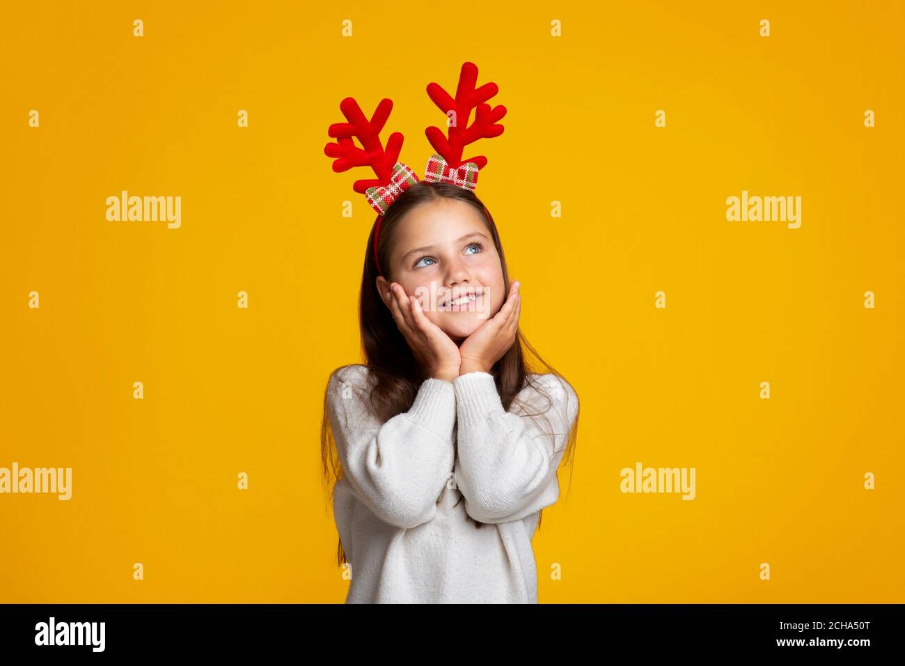 Weihnachtsträume. Nachdenkliches Mädchen mit Hörnern, schaut auf leeren Raum Stockfoto