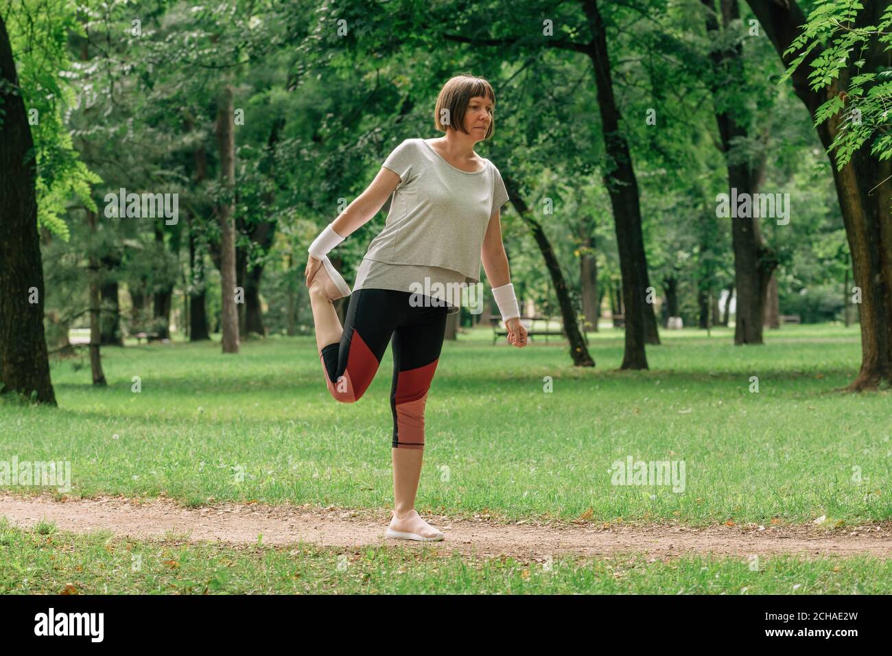 Weibliche Jogginghose, die Muskeln dehnt und sich zum Laufen im Park aufwärmt, selektiver Fokus Stockfoto