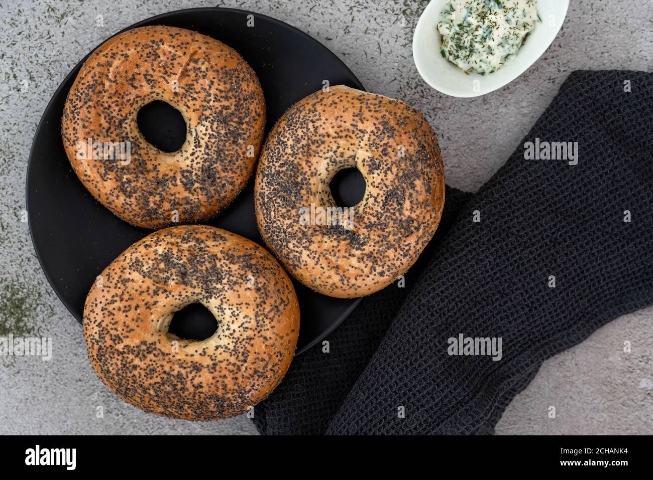Bagels auf einem schwarzen Teller, der auf einer Marmortheke angeordnet ist Stockfoto