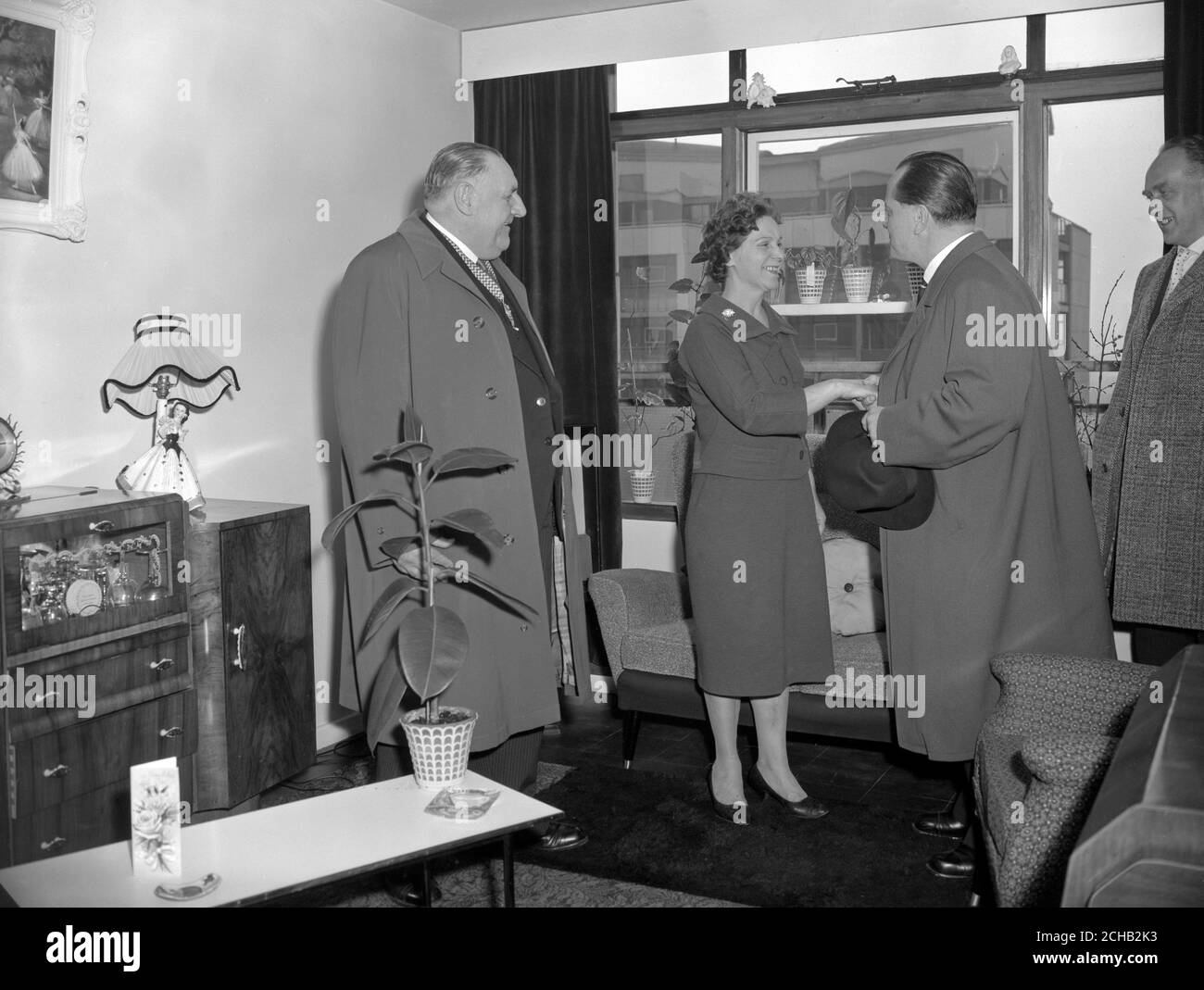 Herr Paul Lucke, Bundesminister für Wohnungsbau, schüttelt Renee O'Brien die Hand bei einem Besuch ihrer Wohnung im Cornish House, einem neu fertiggestellten 18-stöckigen Dreizimmerwohnblock in Southwark, London. Auf der linken Seite ist E.E. Woods, stellvertretender Vorsitzender des London County Council. Stockfoto