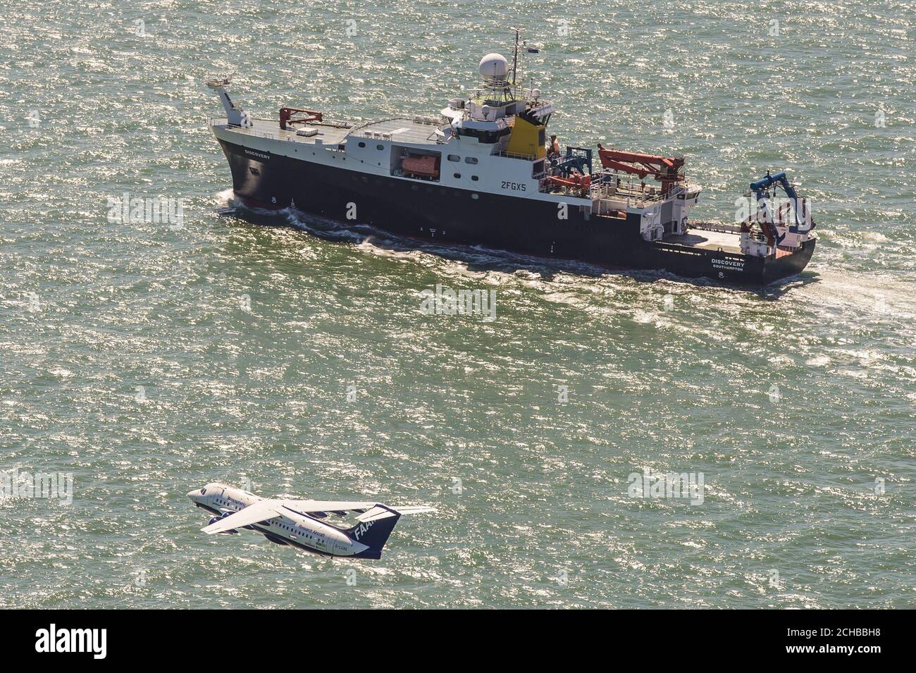 Das britische Natural Environment Research Council (NERC)-Flugzeug, genannt Facility for Airborne Atmospheric Measurements (FAAM) und Schiff RSS Discovery zusammen in der Solent vor der Isle of Wight und Portsmouth. Stockfoto